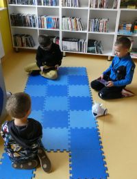 Trzej chłopcy siedzą na podłodze, bawiąc się robotami Photon z wykorzystaniem tabletów
