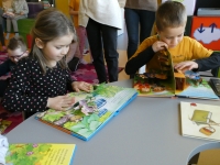 Dziewczynka i chłopiec oglądają ilustracje w książkach