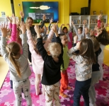Przedszkolaki stoją z uniesionymi rękoma, uczestniczą w zabawie ruchowej
