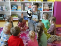 Bibliotekarka prezentuje dzieciom okładkę książki oraz maskotkę krowy
