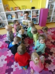 Bibliotekarka pokazuje dzieciom ilustrację w książce