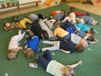 Grupa dzieci leży na dywanie naśladując śpiącego bohatera opowiadania