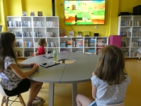 Troje dzieci gra na konsoli Nintendo Switch, siedząc przy stole
