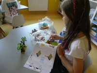 Dziewczynka układa na stoliku klocki LEGO